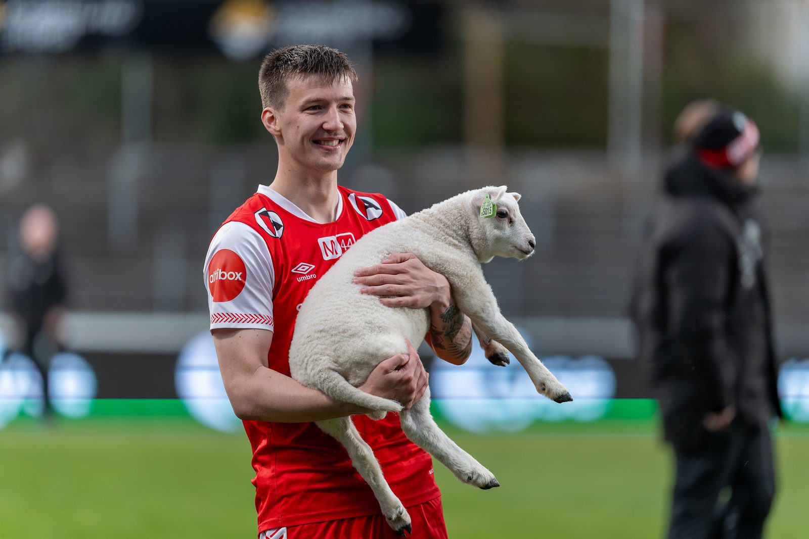 Bryne FK-spiller med et lam i armene på Bryne stadion