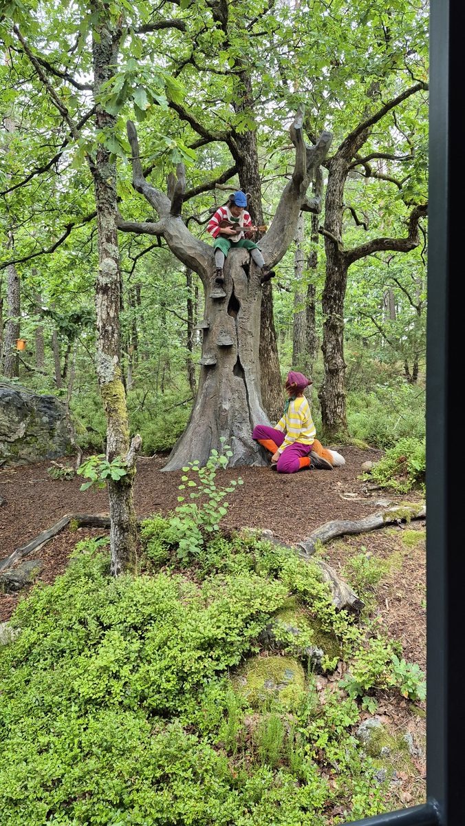 Skuespillere i kostymer ved det utskårne treet i Hakkebakkeskogen
