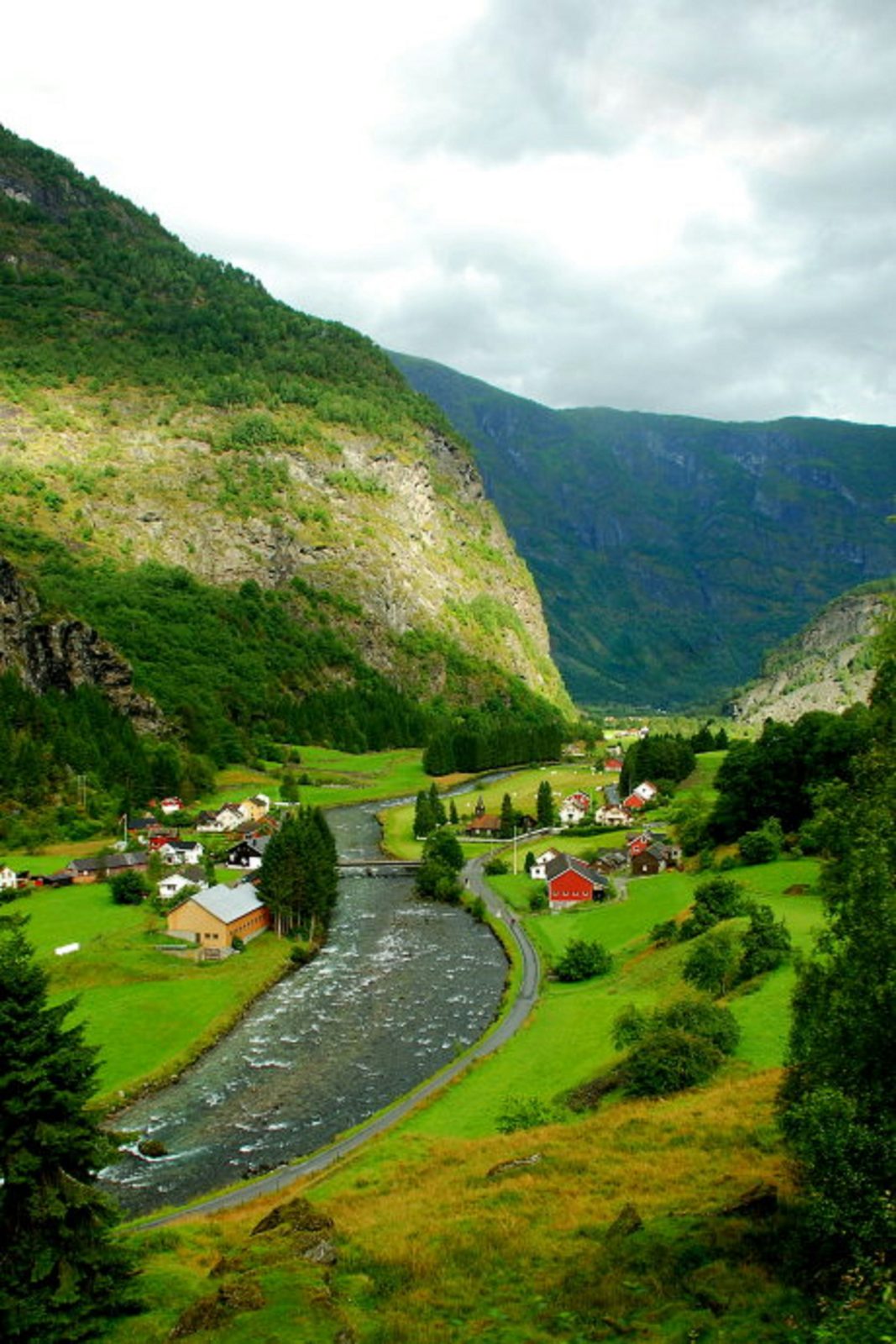 Flåmsdalen sett ovenfra, med elva og bygda mellom bratte, grønne fjellsider