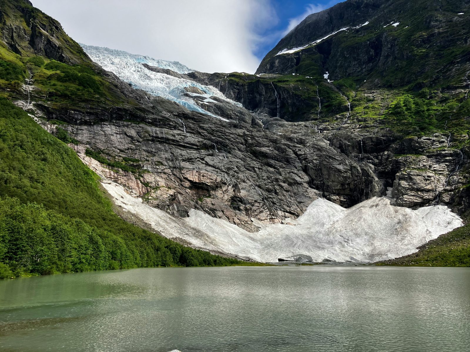 Brearm i Oldedalen med snøfonn ned mot det grønne brevannet, omgitt av bratte fjellsider og småfosser