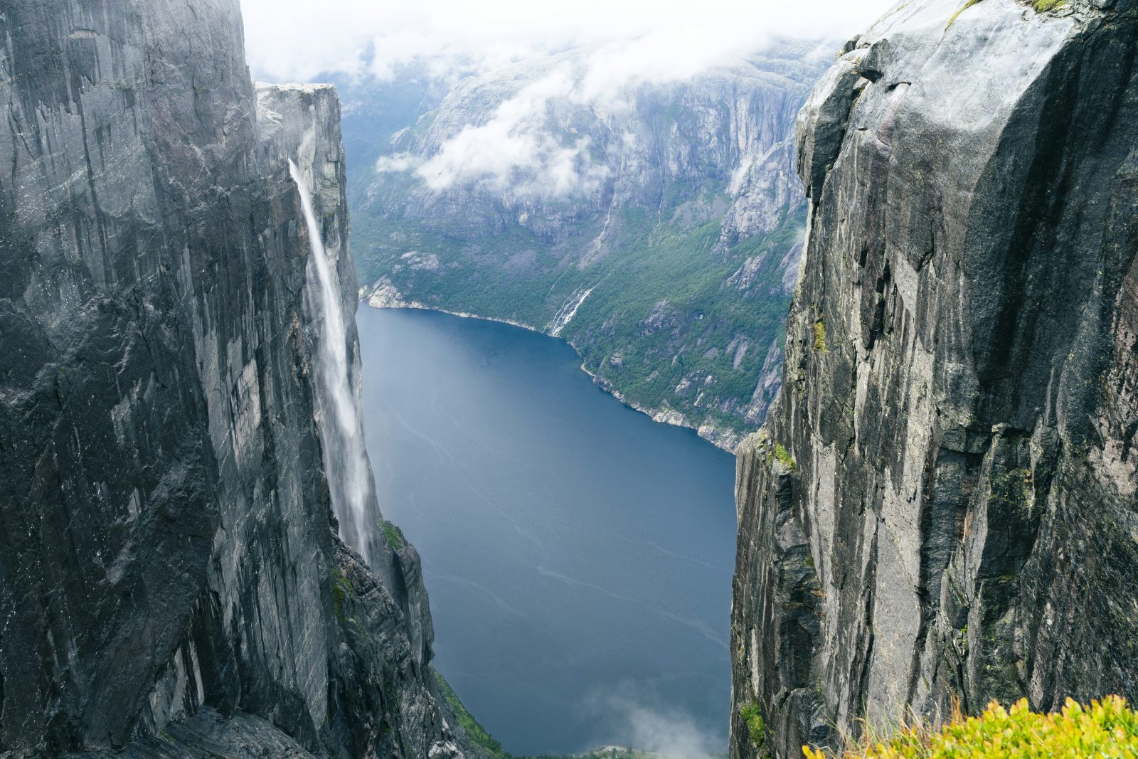 Utsikt fra Kjerag-platået ned mot Lysefjorden, med en foss som styrter utfor granittveggen