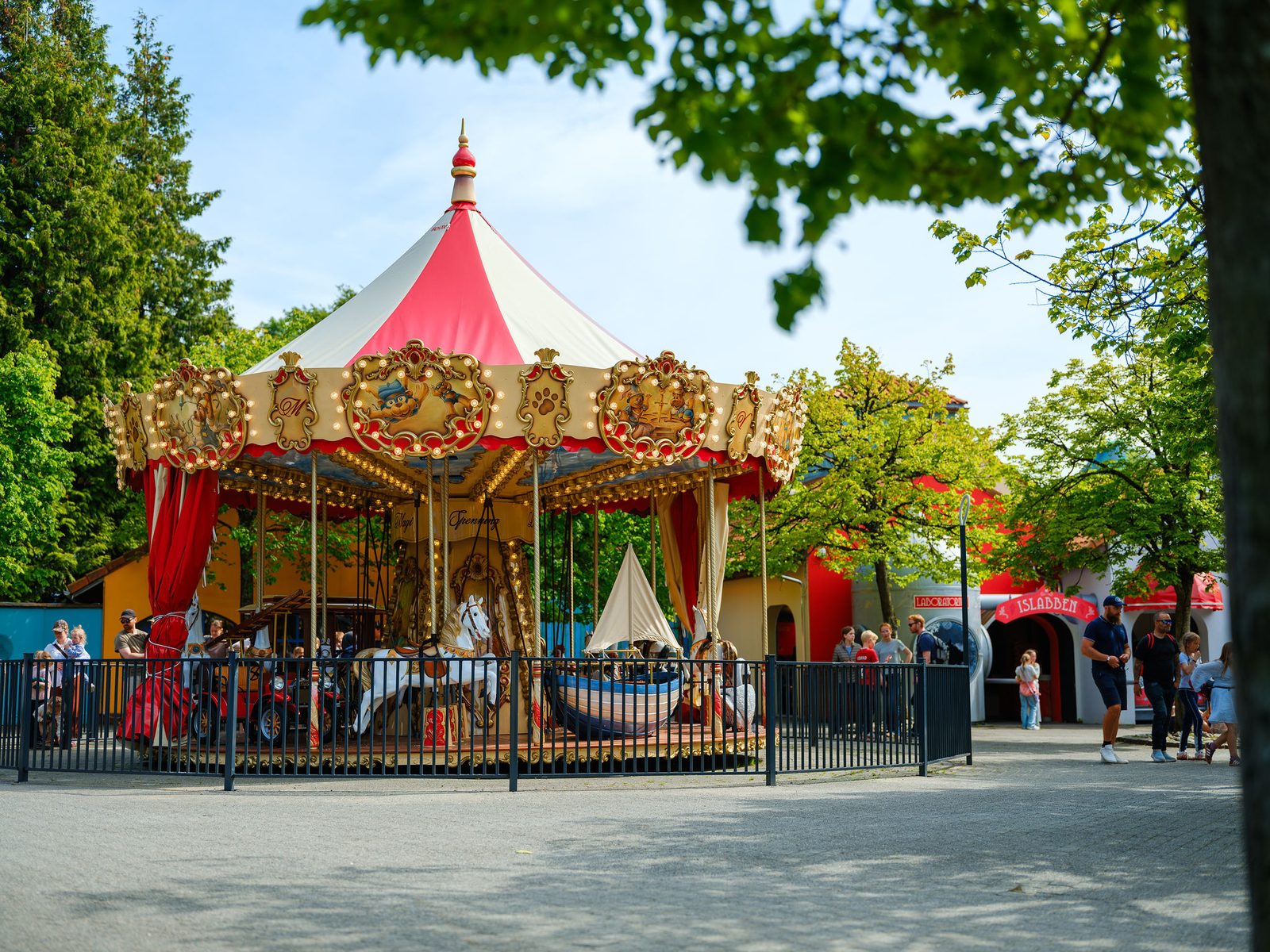 Klassisk karusell med rødt og hvitt tak og gulldetaljer i Kongeparken