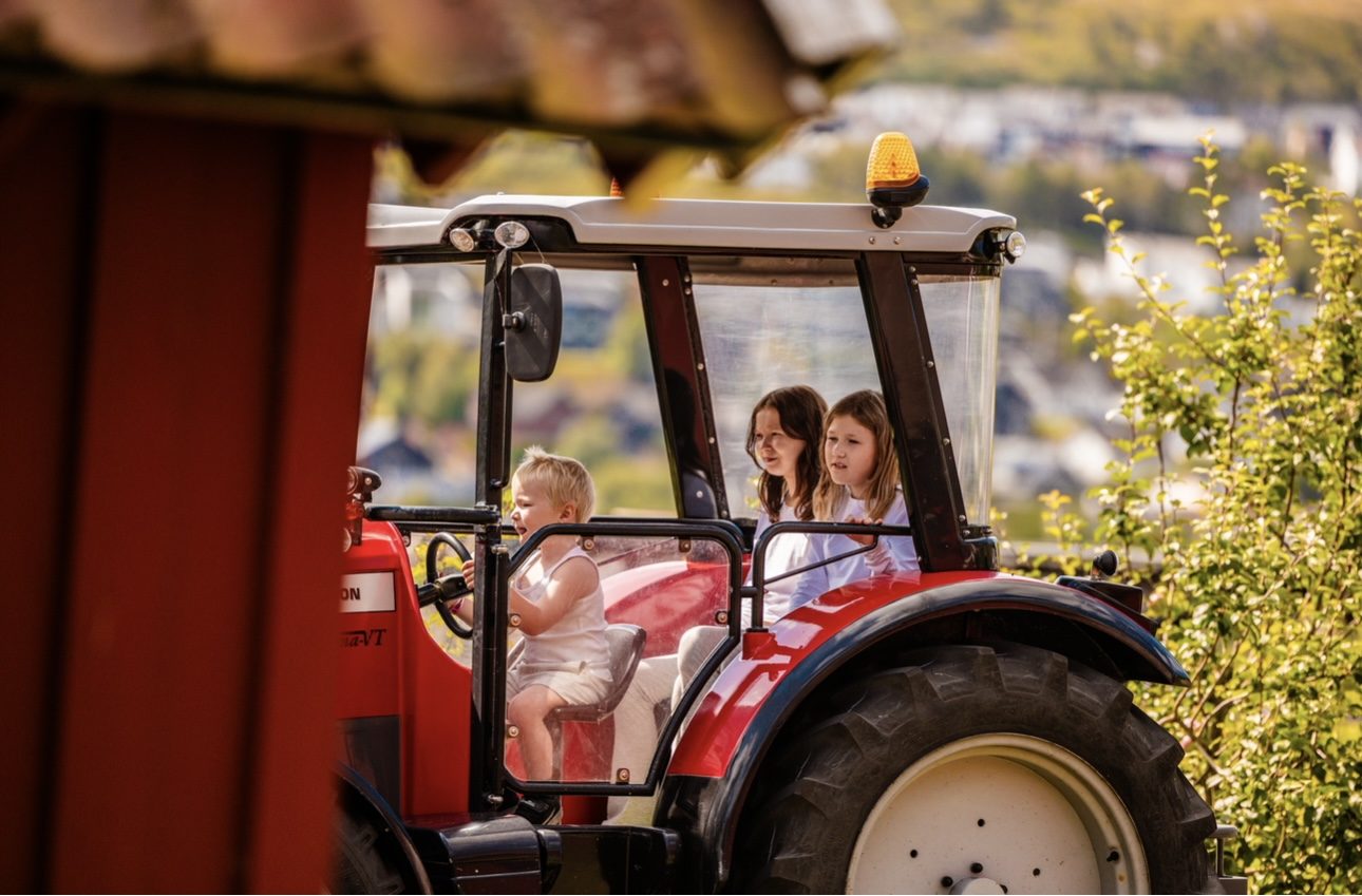 Barn som kjører rød traktor i Gråtassland i Kongeparken