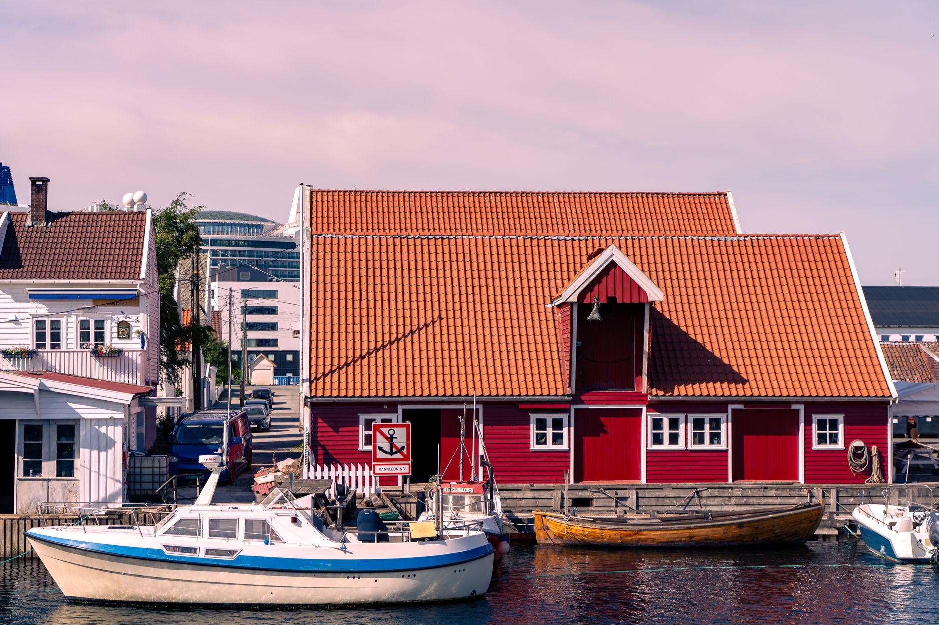 Rødt sjøhus, hvite trehus og småbåter i havna i Kristiansand
