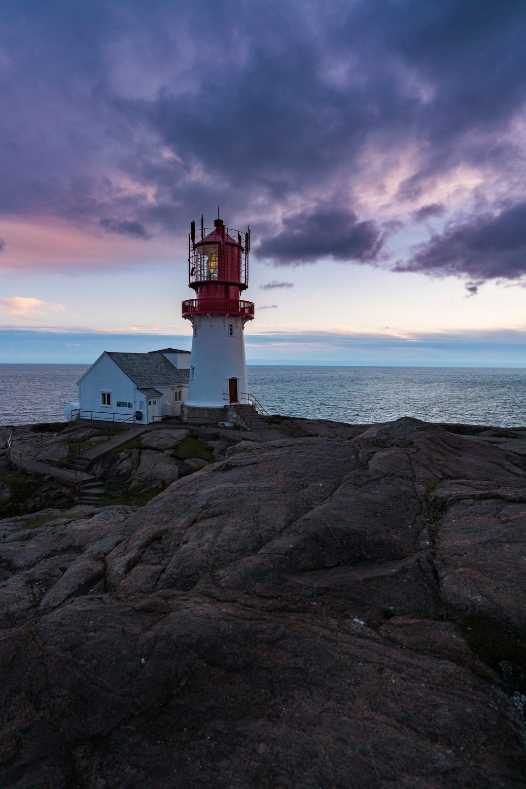 Lindesnes fyr i skumring under mørke uværsskyer over havet