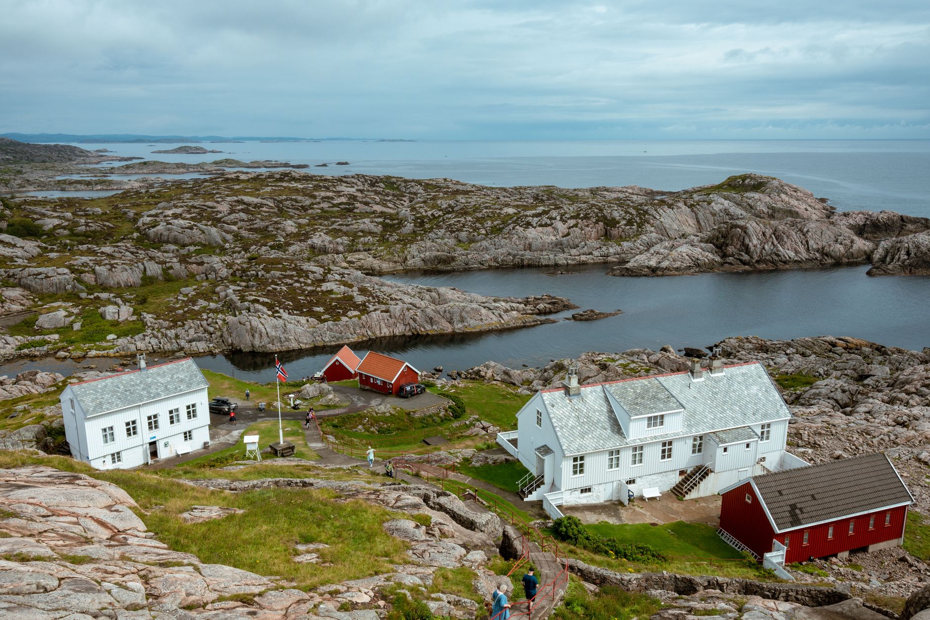 Fyrstasjonens hvite og røde bygninger og den værbitte skjærgården ved Lindesnes