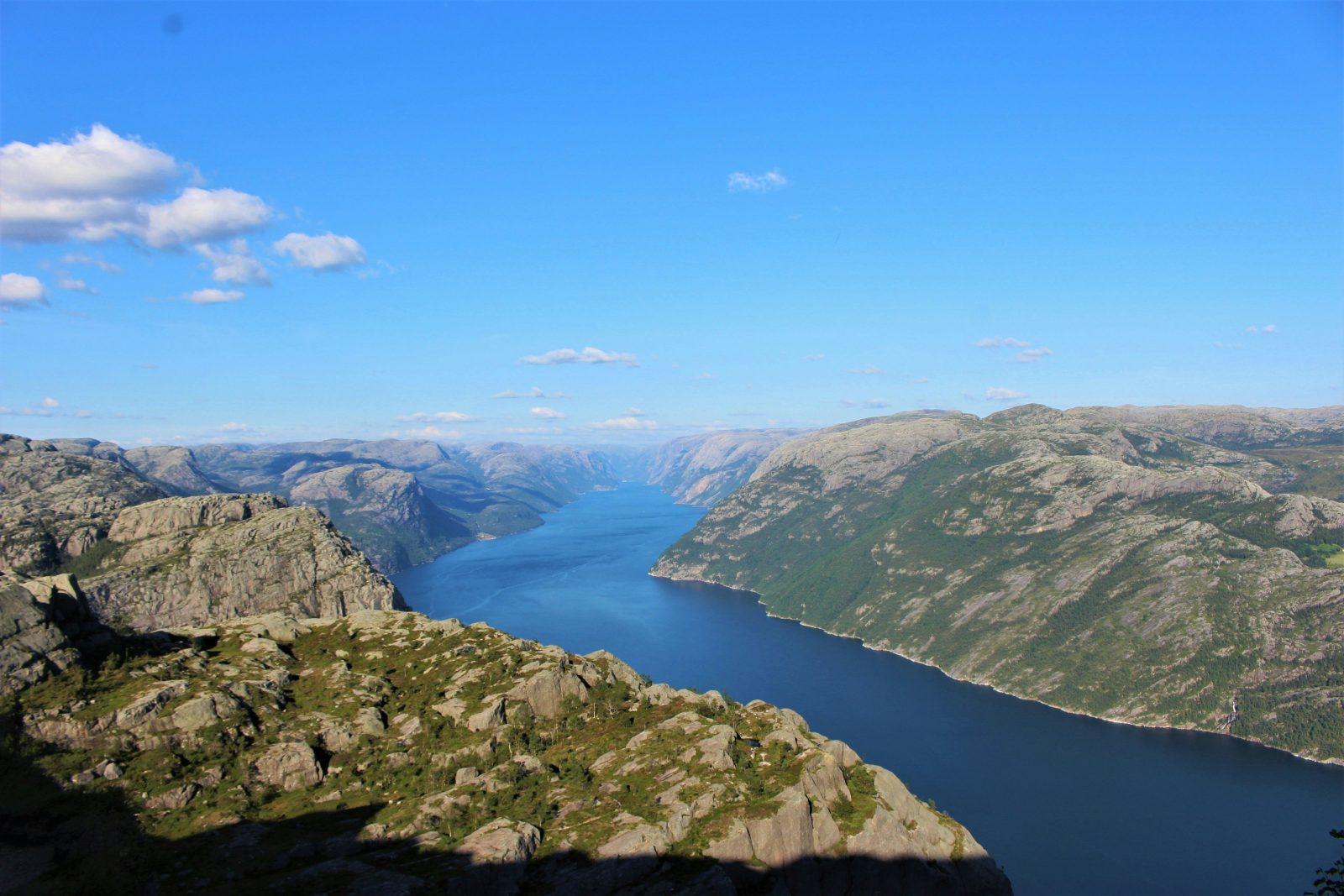 Lysefjorden skjærer seg blå og smal innover mellom lyse granittfjell, sett fra høyden en klarværsdag