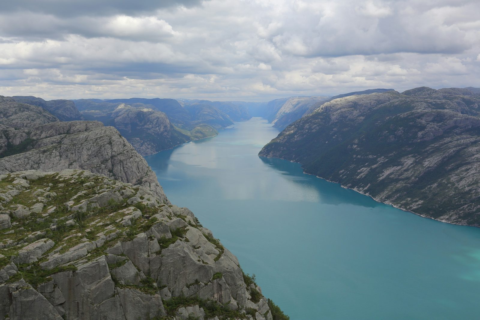 Den turkise Lysefjorden sett ovenfra ved Preikestolen, med granittplatåer i forgrunnen og fjorden som forsvinner innover