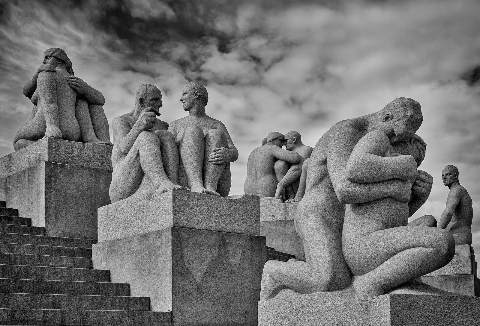 Granittskulpturer av mennesker på Monolittplatået i Vigelandsparken mot dramatisk himmel