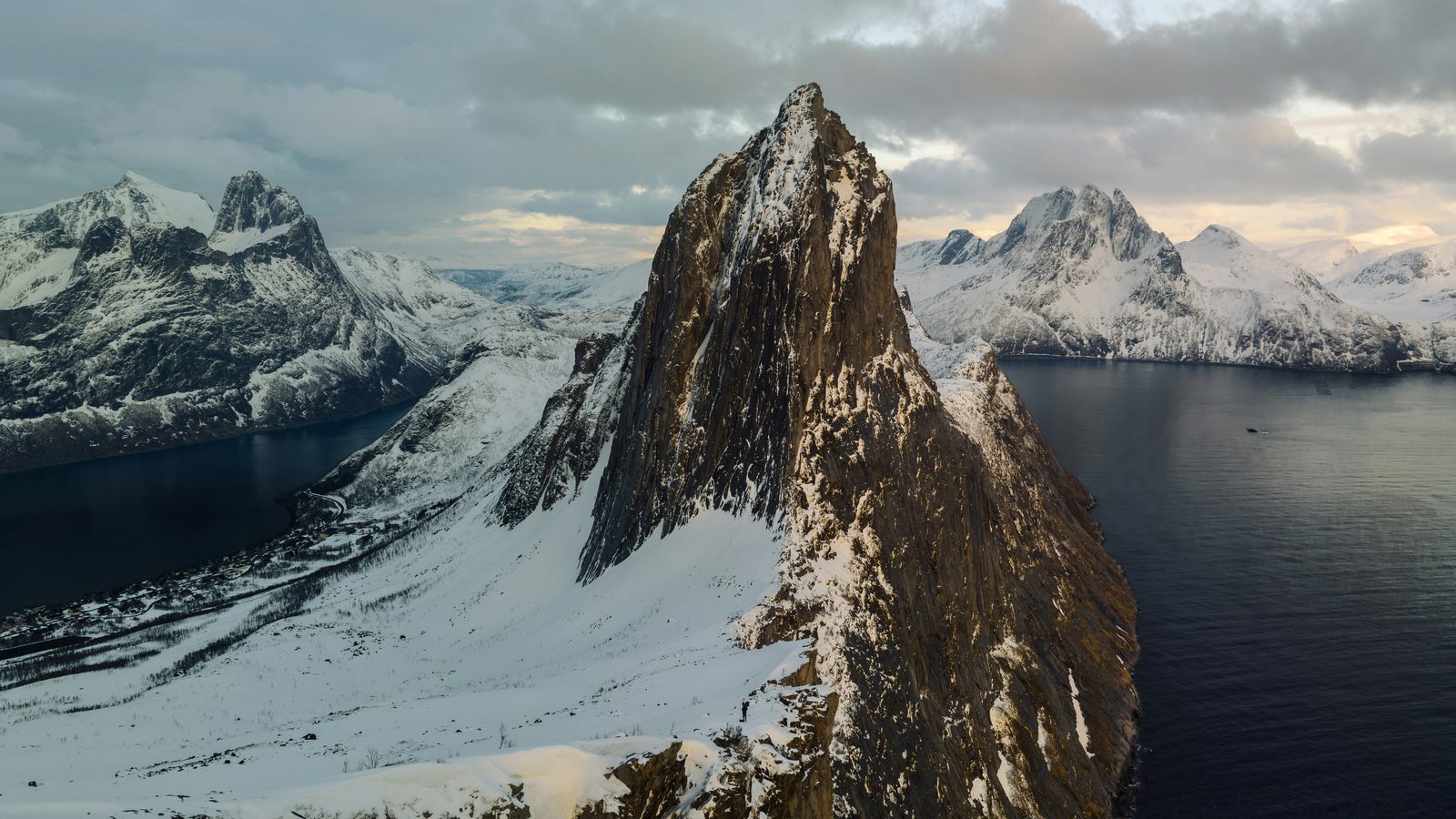 Segla-fjellet reiser seg bratt opp av fjorden på Senja, med snøkledde tinder rundt