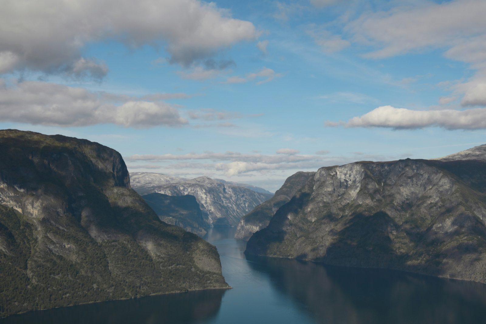 En smal arm av Sognefjorden sett fra høyden, med stupbratte fjellvegger som speiler seg i det blanke vannet