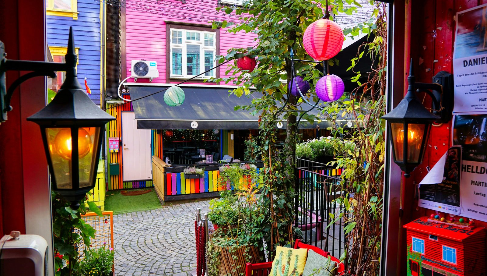 Fargerik bakgård i Stavanger sentrum med lykter, papirlamper og frodige blomsterkasser