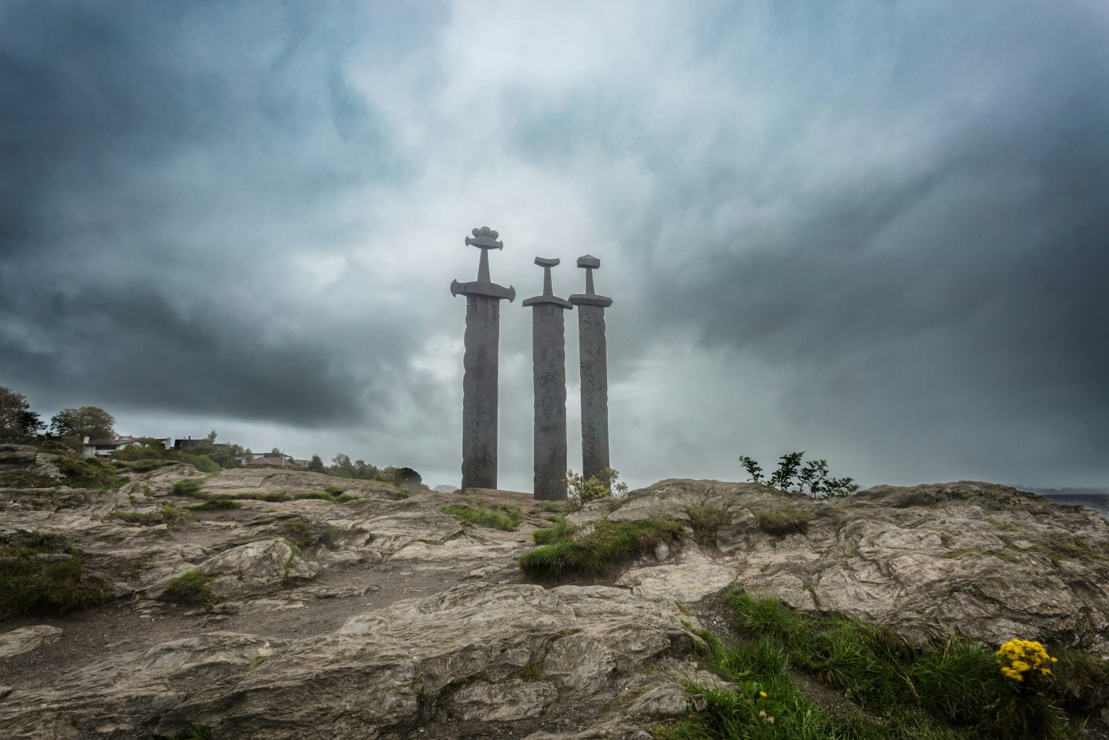 De tre bronsesverdene i Sverd i fjell reiser seg fra svaberget ved Hafrsfjord under dramatisk himmel