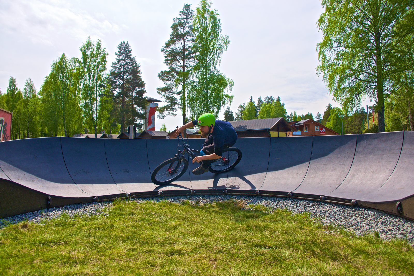Syklist med hjelm lener sykkelen gjennom en dosert sving på pump track-banen