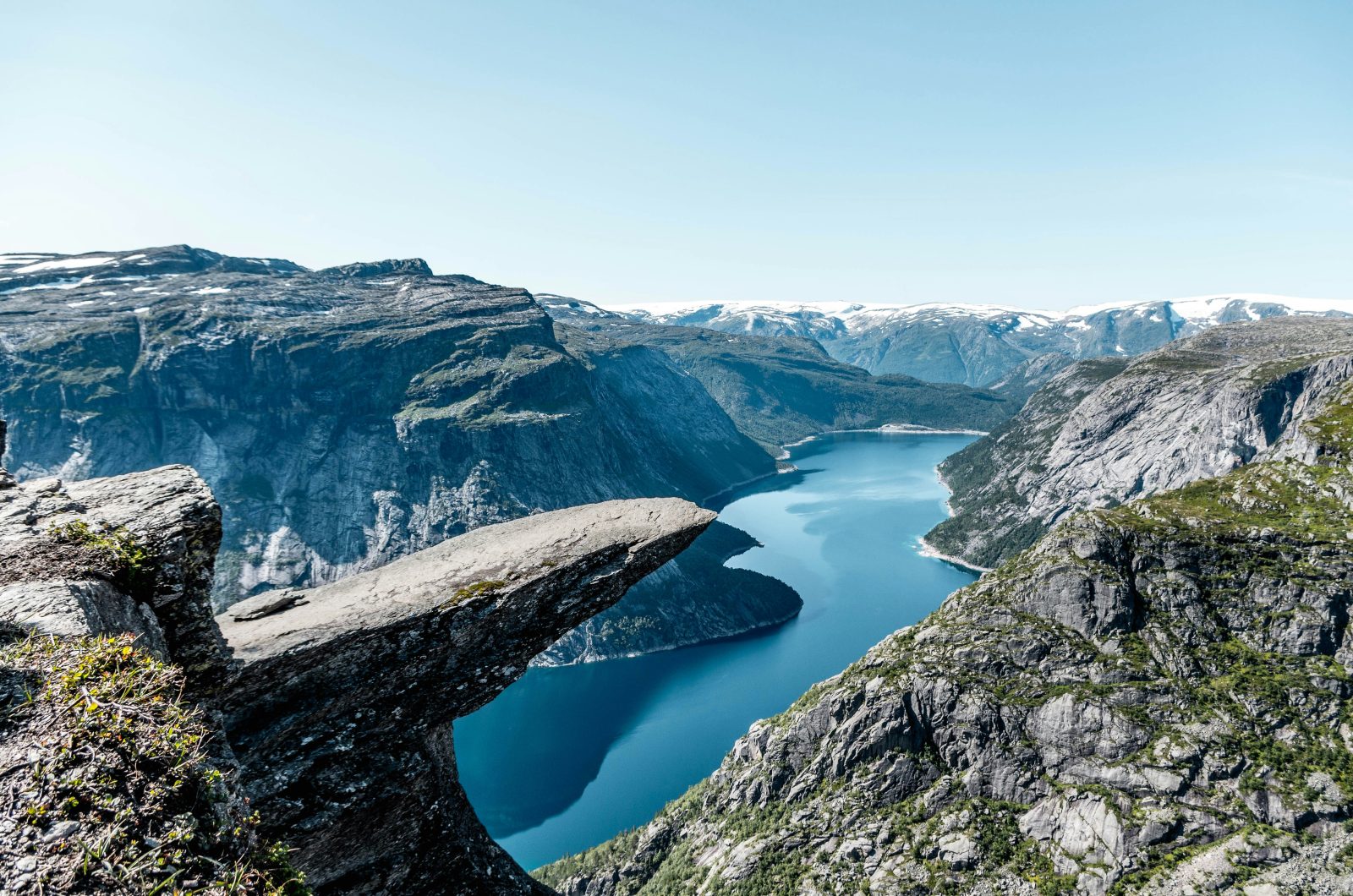 Trolltunga stikker vannrett ut fra fjellet høyt over det blågrønne Ringedalsvatnet en klarværsdag