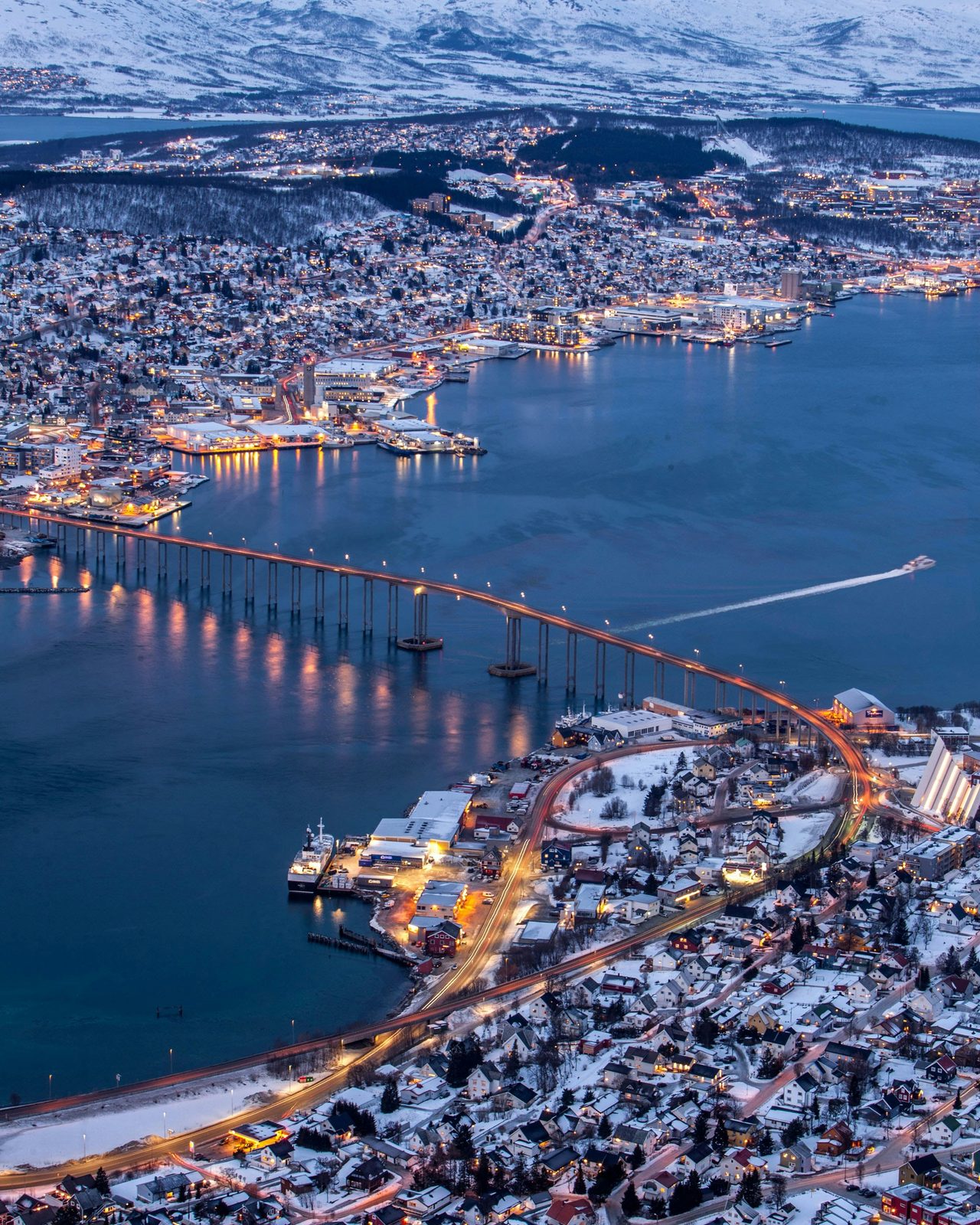 Tromsø sett fra Fjellheisen i blåtimen, med Tromsøbrua, sentrum og snøkledde fjell