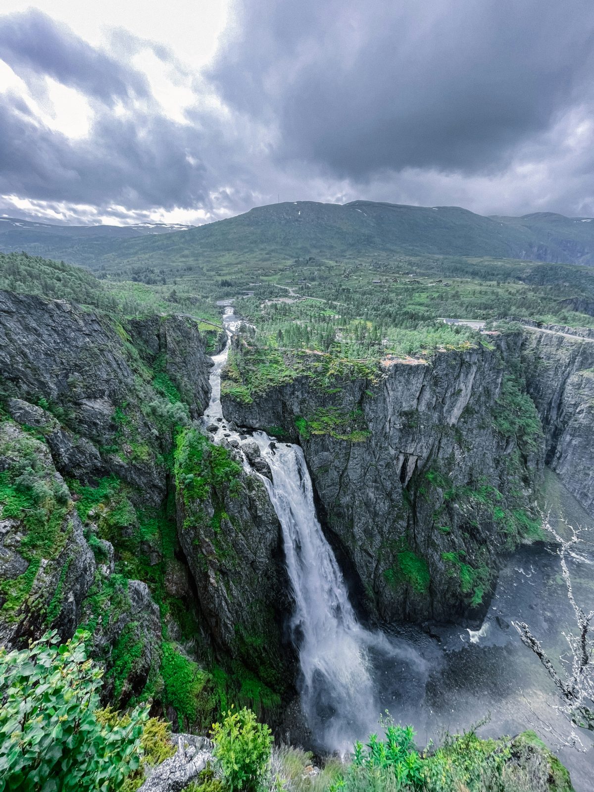 Vøringsfossen styrter fra platået ned i den grønne Måbødalen under mørke skyer