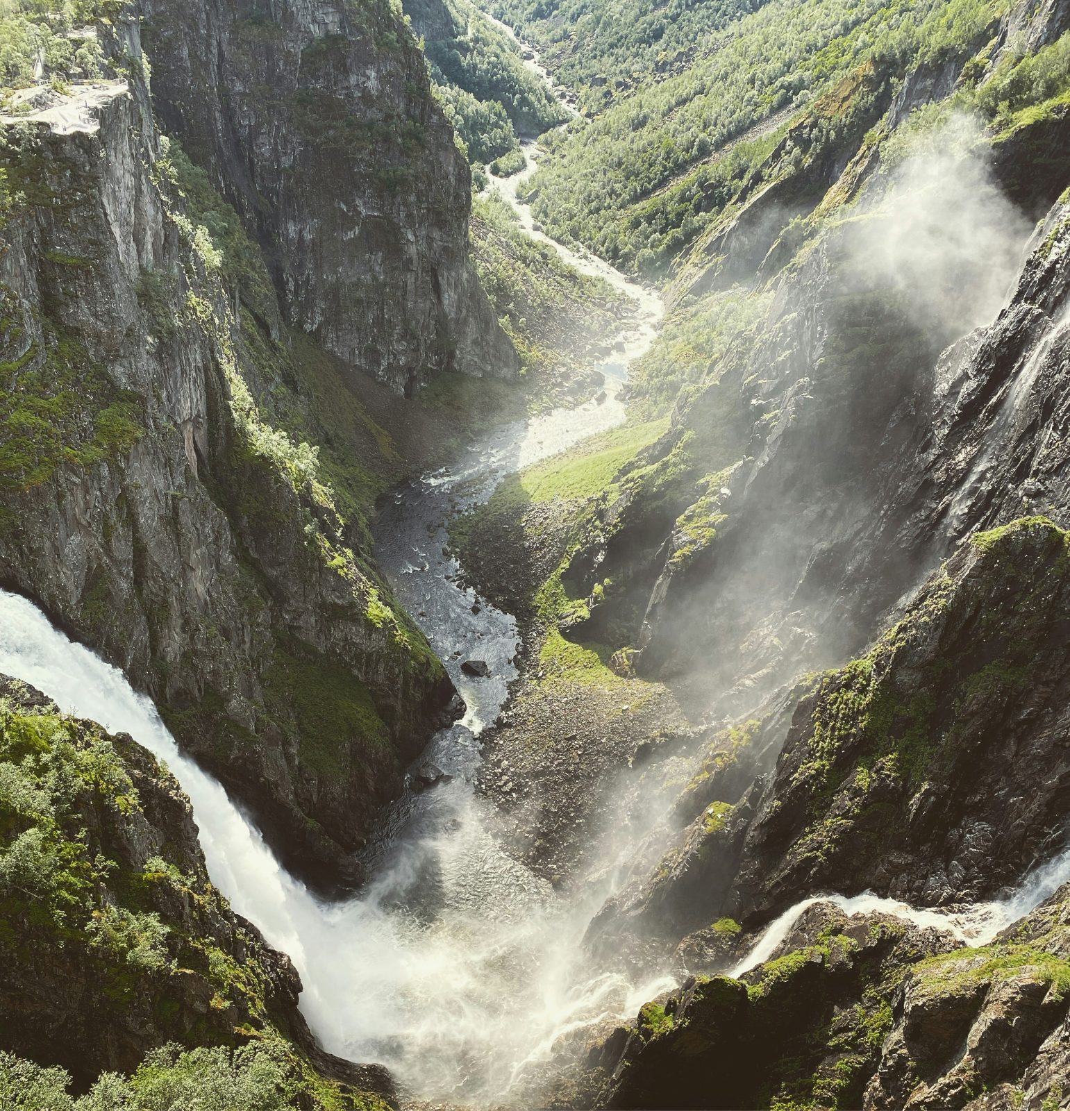 Fossene i Vøringsfossen sett ovenfra, med foss-sprøyt i lufta og elva som slynger seg videre nedover Måbødalen